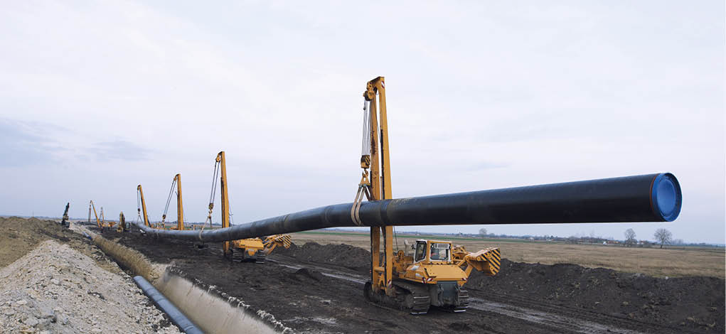 Heavy duty construction machines carrying and placing gas pipe into the ground 