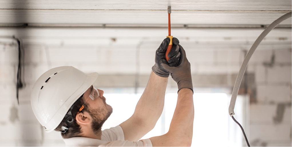 Electrician installer with a tool in his hands  working with cable on the construction site  Repair and handyman concept  House and house reconstruction 