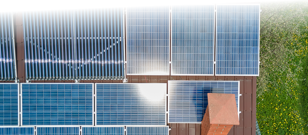 Building roof with rows of blue photovoltaic panels and vacuum air solar collectors for water heating and producing clean ecological electricity. Renewable electric and heat energy with zero emission.