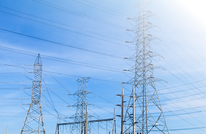 High voltage towers. The meadow below. Industry and nature coexist in appropriate Slightly cloudy sky.