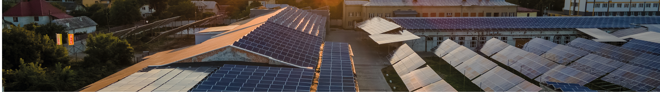 Aerial view of solar power plant with blue photovoltaic panels mounted on industrial building roof for producing green ecological electricity at sunset. Production of sustainable energy concept.