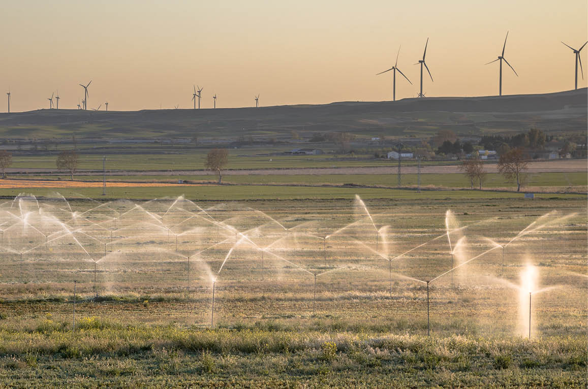 Irrigation sprinklers watering farmland at sunset in Huesca area, Spain.