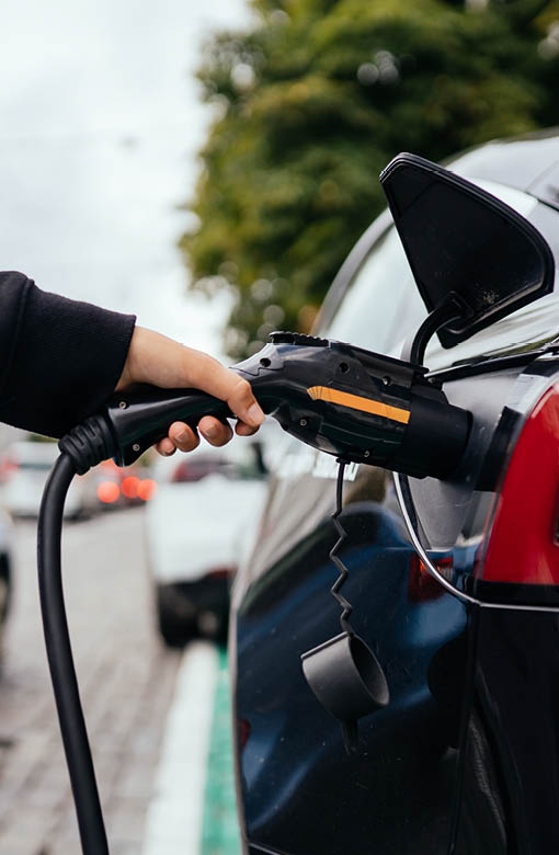 Woman near car. Vehicle charged at the charging station.