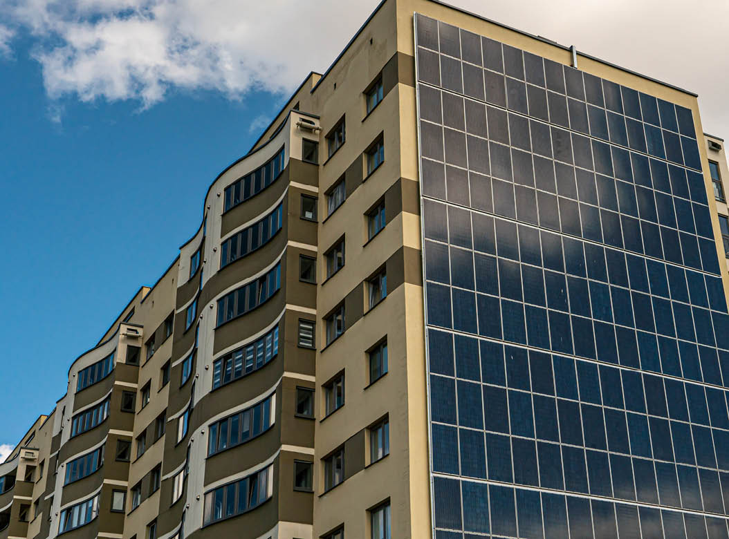 Movement of clouds against the background of a modern energy-efficient building. Multi-storey residential building with solar panels on the wall. Renewable energy in the city