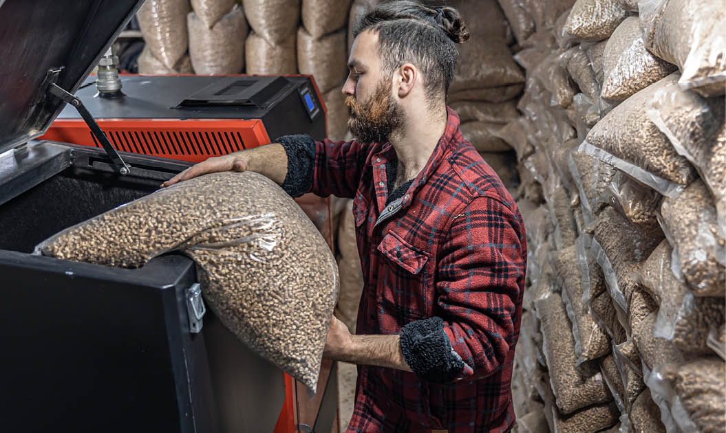 The man loads the pellets in the solid fuel boiler, working with biofuels, economical heating.