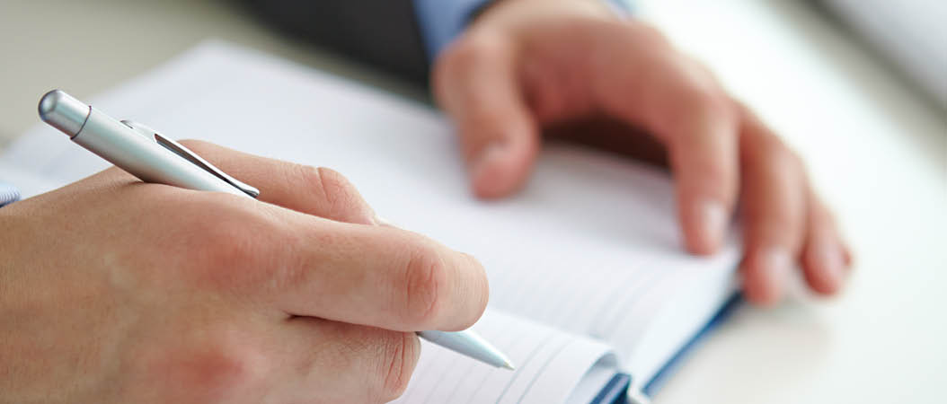 Businessman hand with pen over open notebook making report