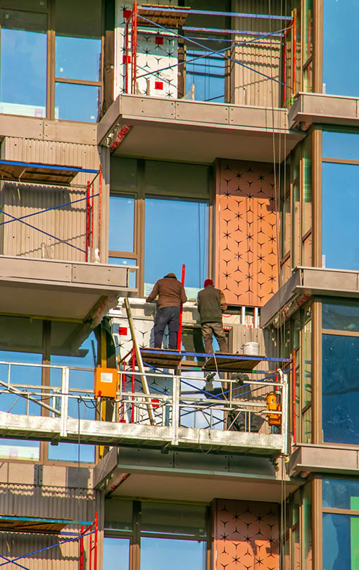 Suspended platform, construction cradle hanging on building. Installation and repair work. Building facades construction works. Facade of high-rise building under construction, finishing works