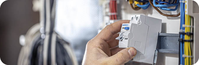 Male electrician at the checkout counter on a blurred background of a switchboard.